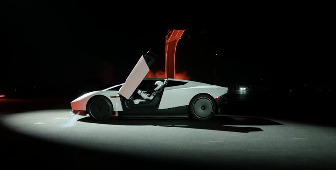 White Roadster concept at night with the door raised under a spotlight